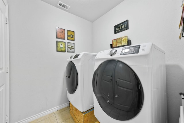 clothes washing area featuring separate washer and dryer and light tile patterned floors