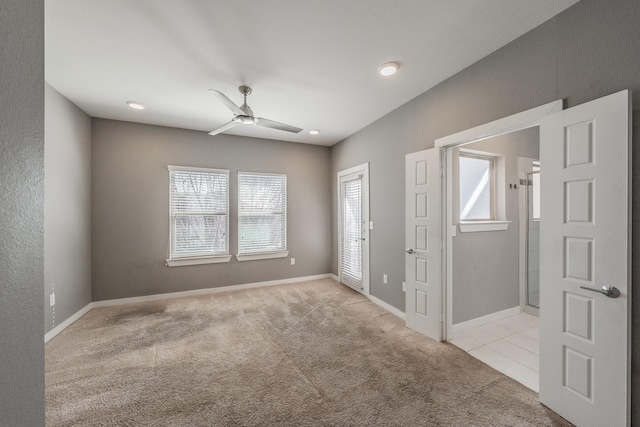 spare room with light carpet, a ceiling fan, and baseboards