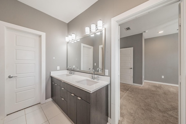 bathroom with double vanity, baseboards, visible vents, and a sink