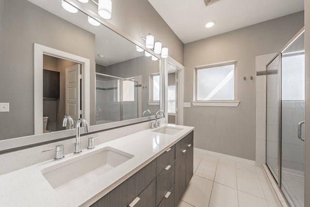 bathroom featuring double vanity, a stall shower, a sink, and tile patterned floors