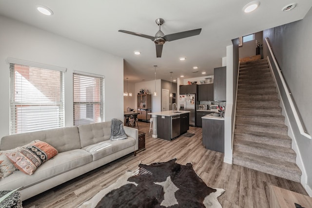 living area with light wood-style flooring, stairway, ceiling fan, and recessed lighting