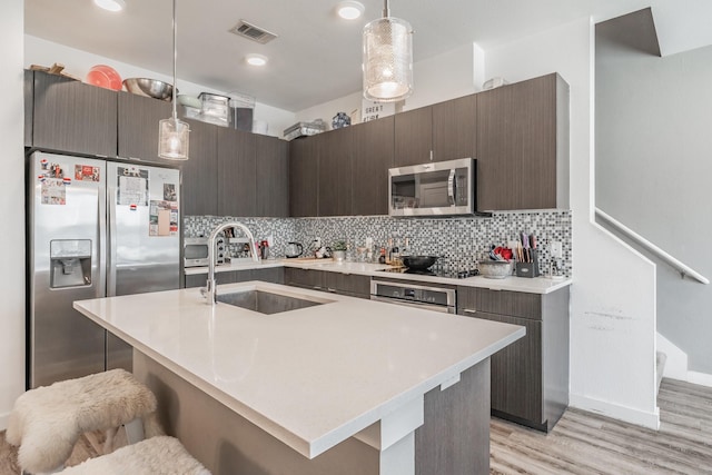 kitchen with visible vents, decorative backsplash, appliances with stainless steel finishes, light countertops, and a sink