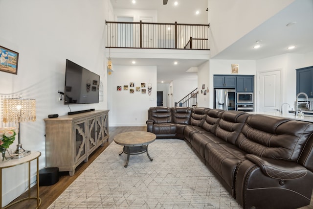 living room with a high ceiling, sink, and wood-type flooring