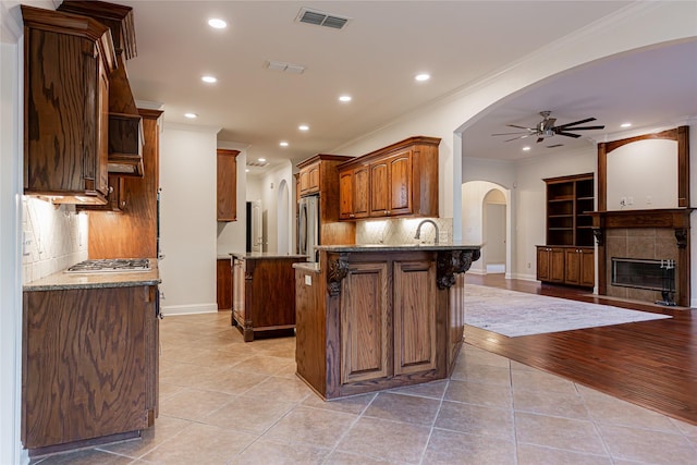 kitchen featuring stainless steel appliances, crown molding, light tile patterned floors, and dark stone counters