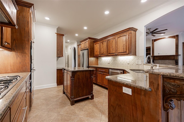 kitchen with appliances with stainless steel finishes, dark stone counters, ceiling fan, sink, and a center island