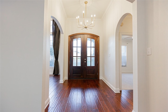 foyer entrance featuring dark hardwood / wood-style floors, crown molding, a chandelier, and french doors