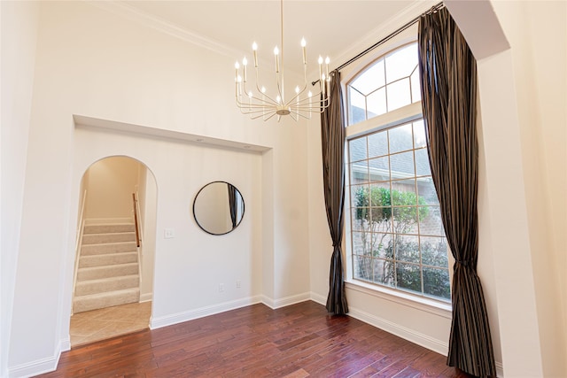 empty room featuring crown molding, dark hardwood / wood-style floors, and a notable chandelier