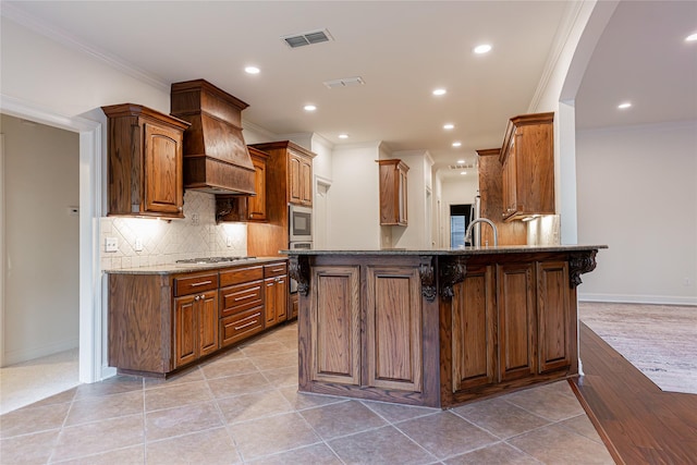 kitchen with premium range hood, a kitchen bar, tasteful backsplash, kitchen peninsula, and stone counters