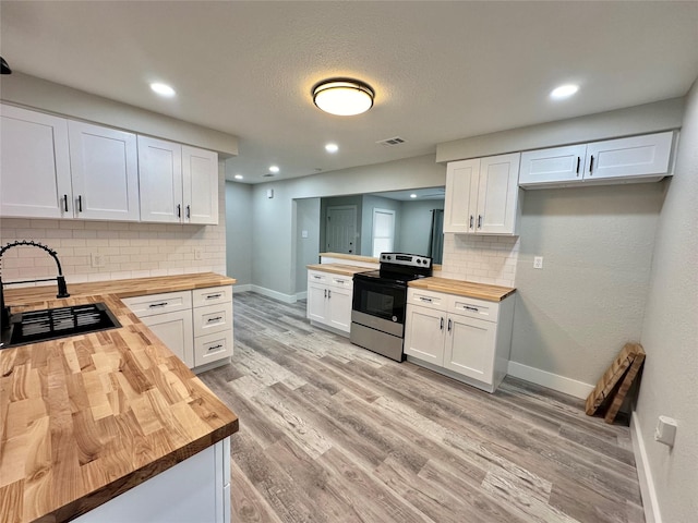 kitchen with wooden counters, backsplash, sink, electric range, and white cabinets