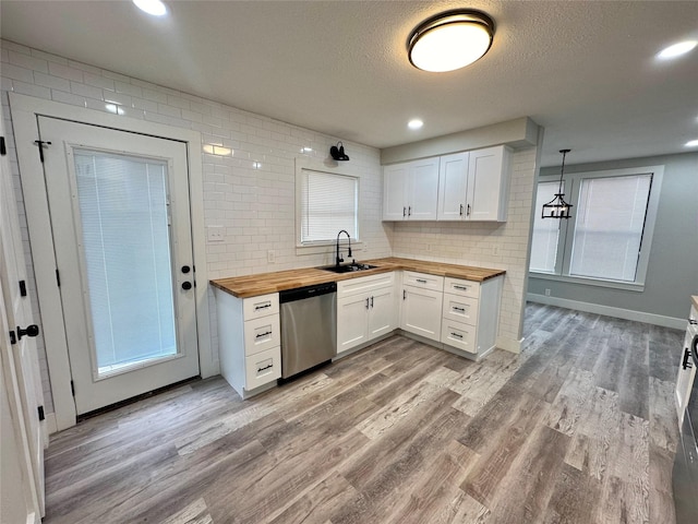 kitchen featuring stainless steel dishwasher, light wood-style floors, white cabinetry, wooden counters, and a sink