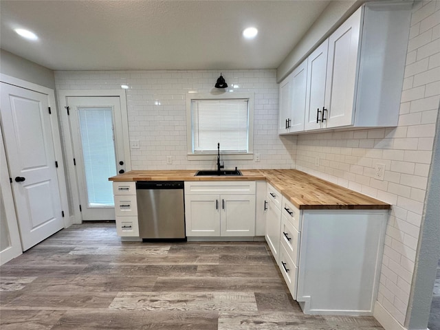 kitchen with tasteful backsplash, wood counters, wood finished floors, stainless steel dishwasher, and a sink