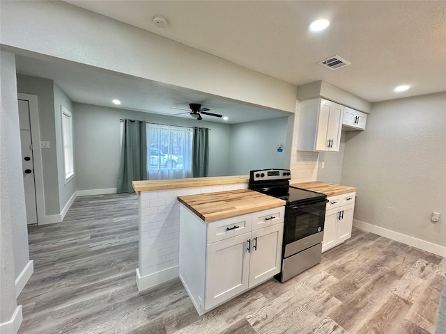 kitchen featuring white cabinets, wooden counters, and electric range