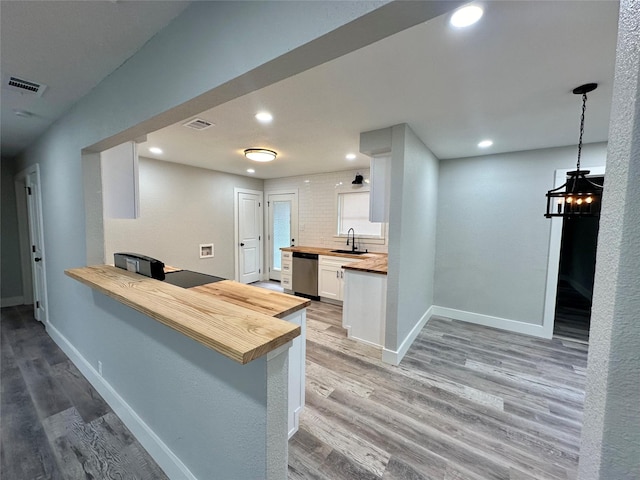 kitchen featuring visible vents, butcher block countertops, a sink, and stainless steel dishwasher