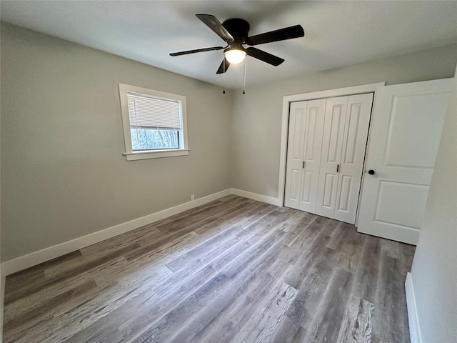 unfurnished bedroom featuring a ceiling fan, a closet, baseboards, and wood finished floors