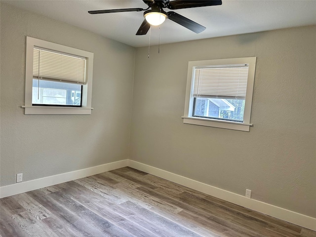 empty room featuring wood-type flooring, a wealth of natural light, and ceiling fan