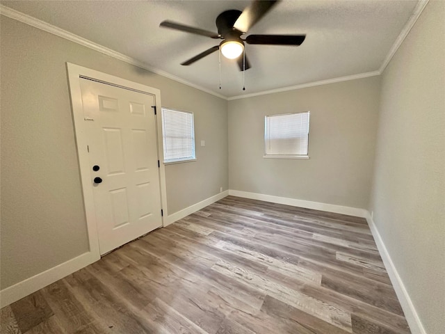 foyer with ceiling fan, ornamental molding, and light wood-type flooring