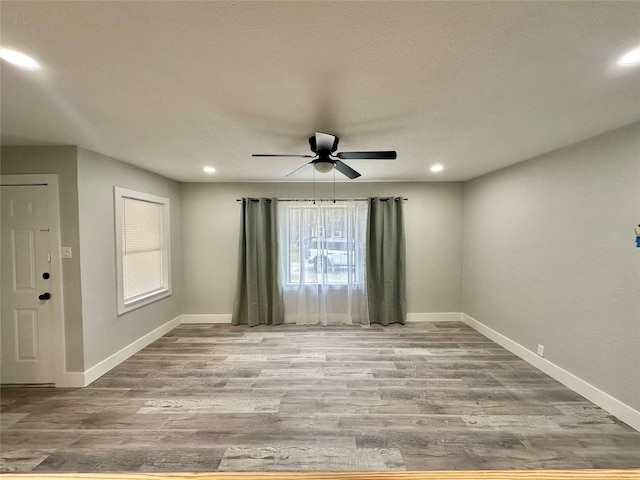 empty room featuring a ceiling fan, recessed lighting, baseboards, and wood finished floors