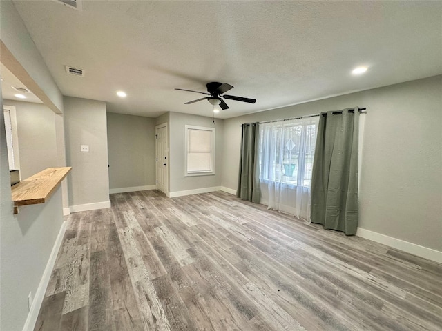 unfurnished living room featuring ceiling fan, a textured ceiling, and light wood-type flooring