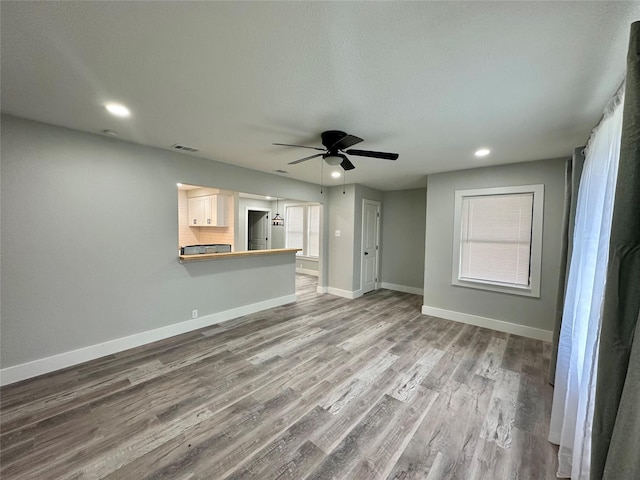 unfurnished living room with ceiling fan, recessed lighting, wood finished floors, visible vents, and baseboards