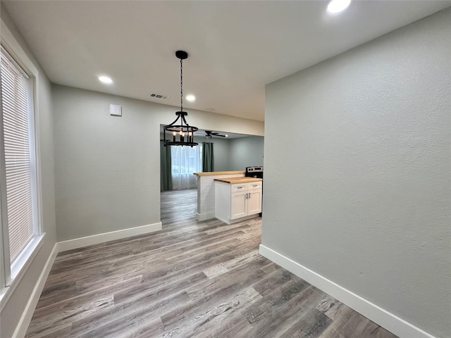 unfurnished dining area featuring recessed lighting, visible vents, baseboards, and wood finished floors