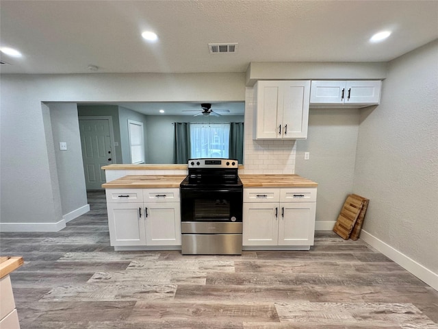 kitchen featuring white cabinetry, backsplash, light hardwood / wood-style floors, wood counters, and stainless steel range with electric cooktop