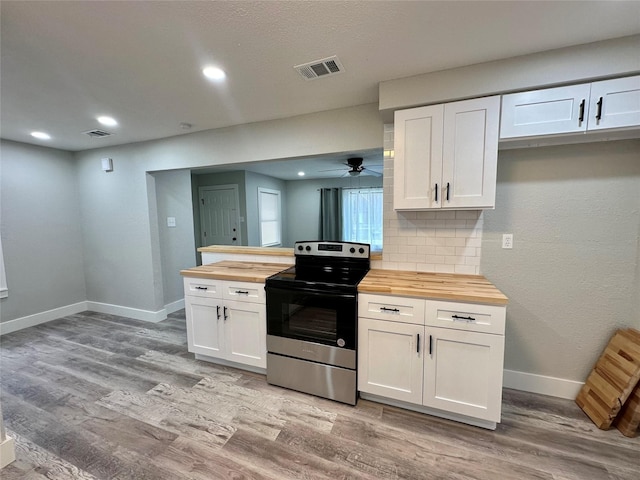 kitchen with butcher block countertops, visible vents, white cabinets, stainless steel electric range oven, and light wood finished floors