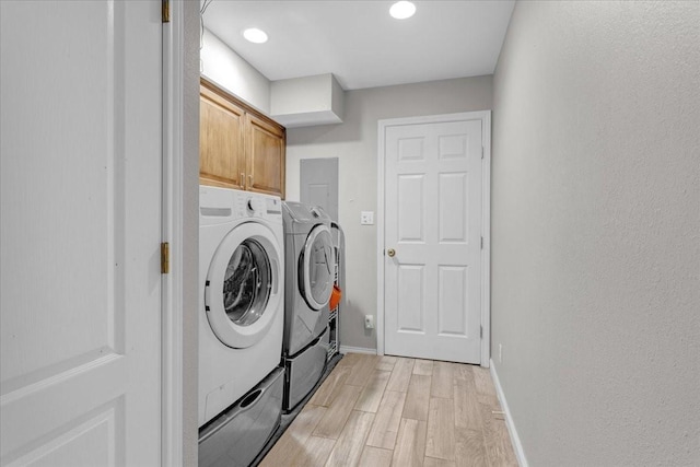 laundry area with washer and clothes dryer, cabinets, and light wood-type flooring