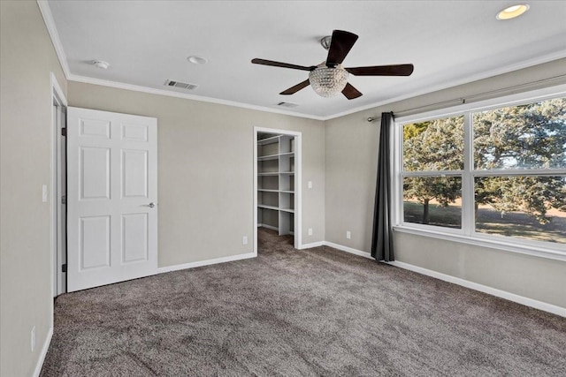 unfurnished bedroom with ceiling fan, carpet flooring, ornamental molding, a spacious closet, and a closet