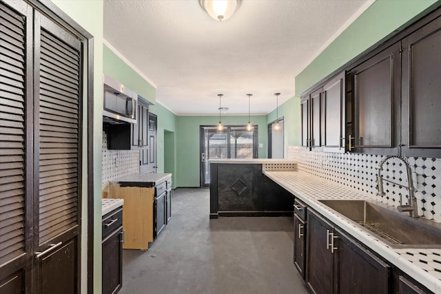 kitchen featuring backsplash, sink, hanging light fixtures, and a textured ceiling