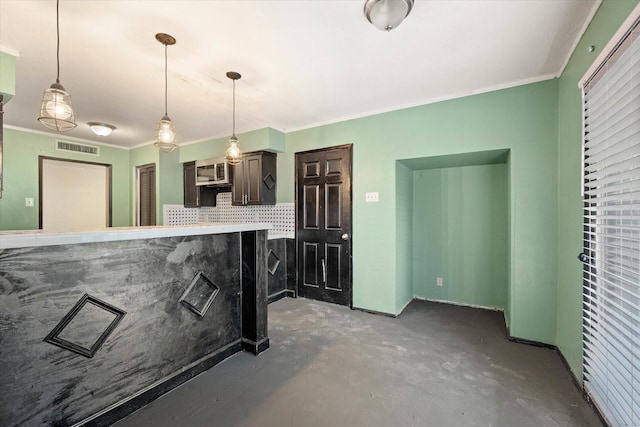 kitchen with hanging light fixtures, ornamental molding, concrete floors, and decorative backsplash