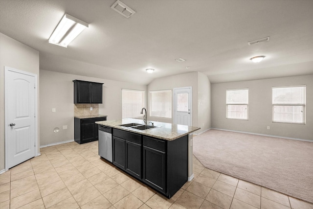 kitchen featuring dishwasher, sink, a kitchen island with sink, light stone counters, and light carpet