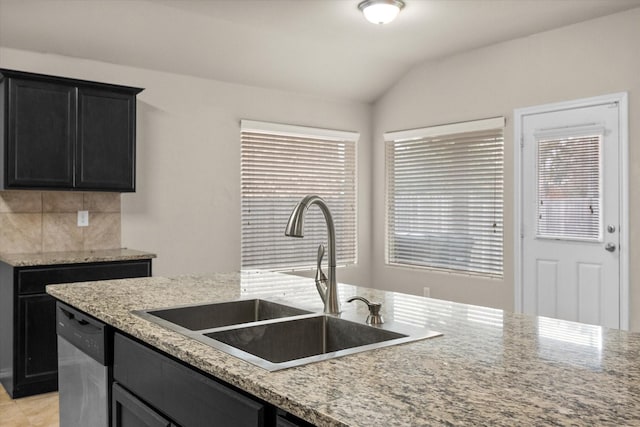 kitchen featuring tasteful backsplash, lofted ceiling, sink, stainless steel dishwasher, and light stone counters