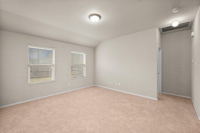 spare room featuring vaulted ceiling and light colored carpet