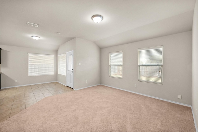 carpeted spare room featuring vaulted ceiling