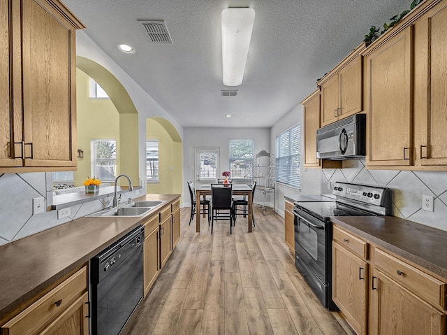 kitchen with tasteful backsplash, a textured ceiling, sink, black appliances, and light hardwood / wood-style flooring