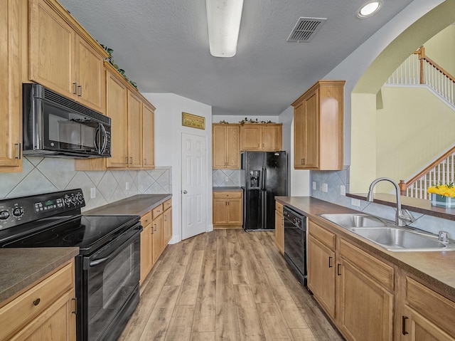 kitchen with sink, light wood-type flooring, backsplash, and black appliances