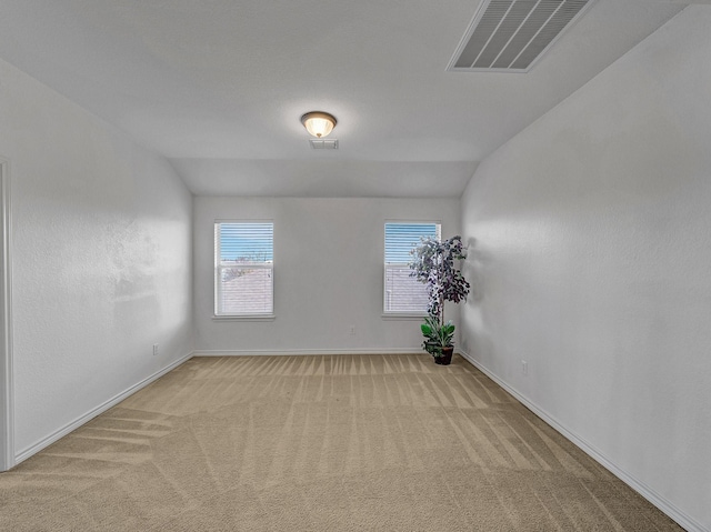 carpeted empty room featuring vaulted ceiling