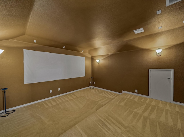 carpeted home theater room with lofted ceiling and a textured ceiling