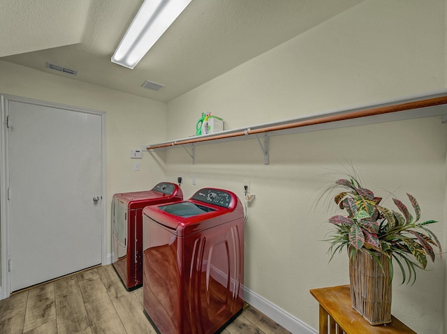 laundry area featuring washing machine and clothes dryer and light hardwood / wood-style floors