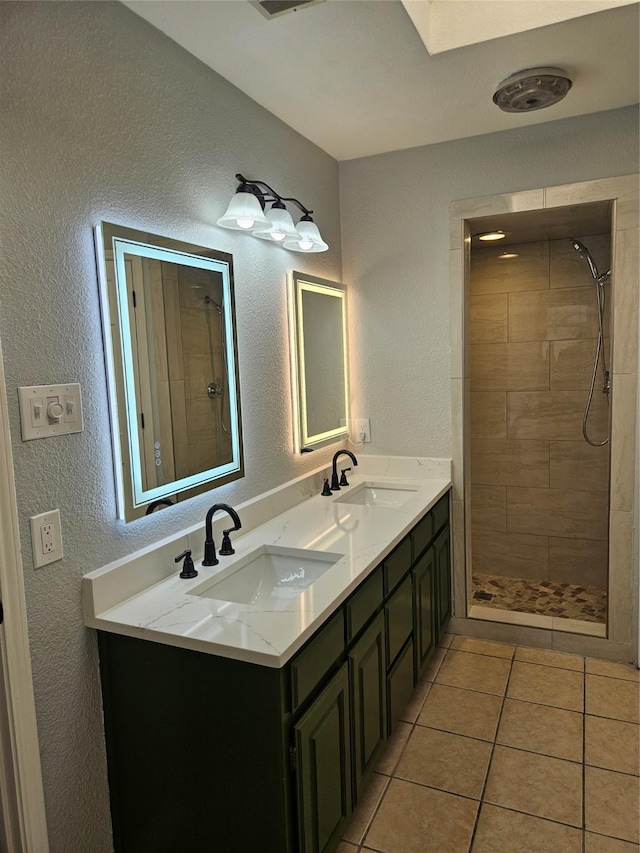 bathroom with tile patterned floors, vanity, and a tile shower