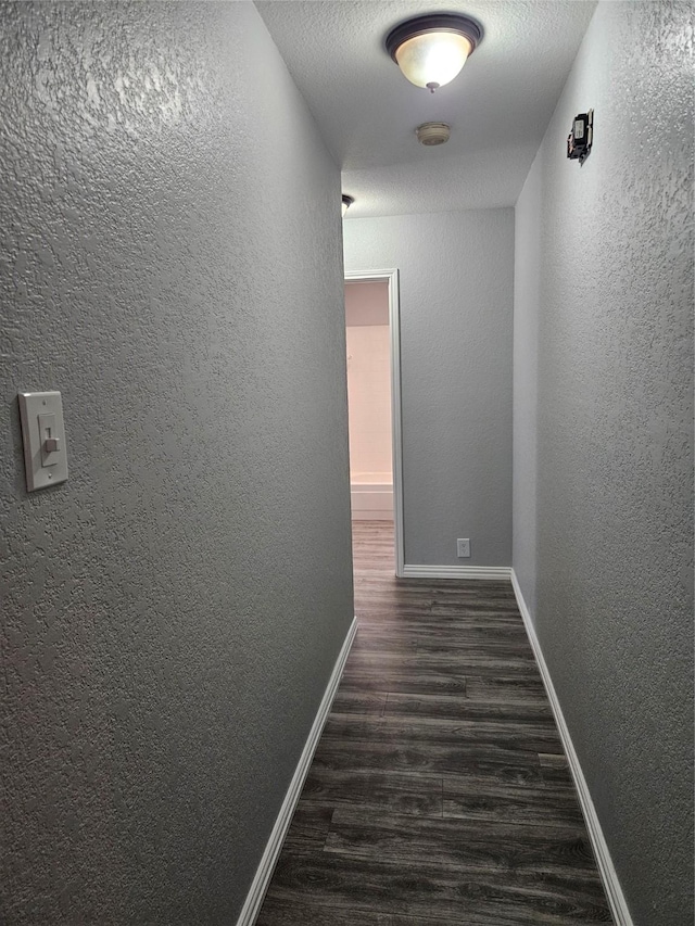 hall with a textured ceiling and dark hardwood / wood-style flooring