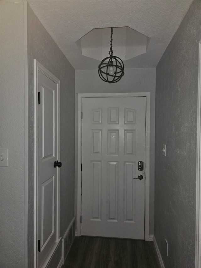 doorway featuring a textured ceiling and dark wood-type flooring