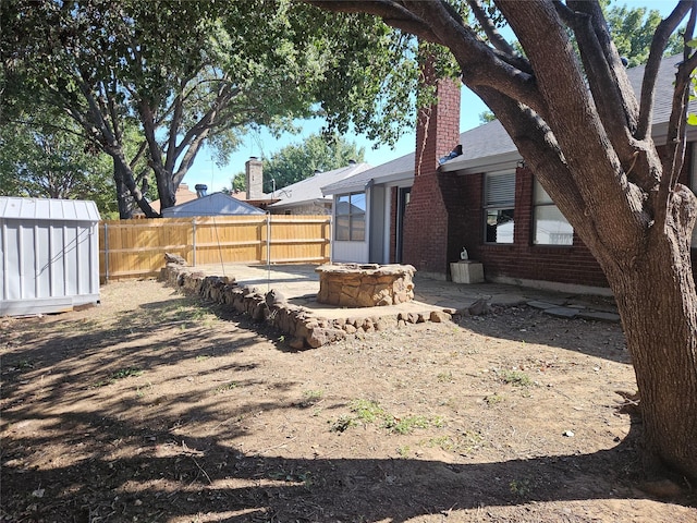 view of yard with a shed and an outdoor fire pit