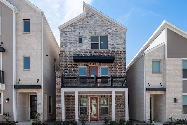 view of front of house with brick siding and a balcony