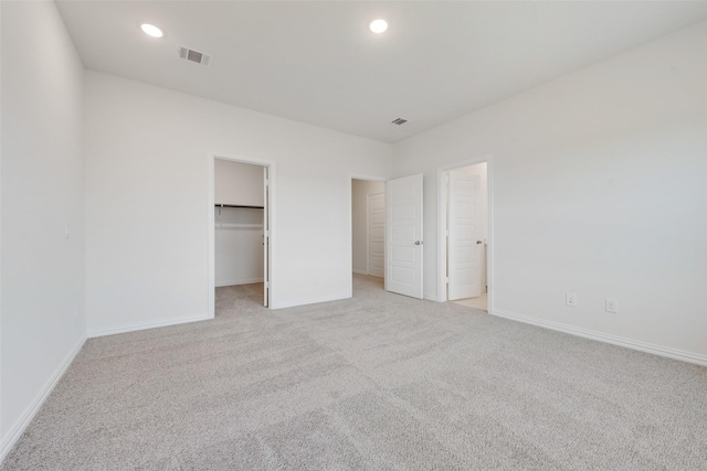 unfurnished bedroom featuring a spacious closet and light carpet