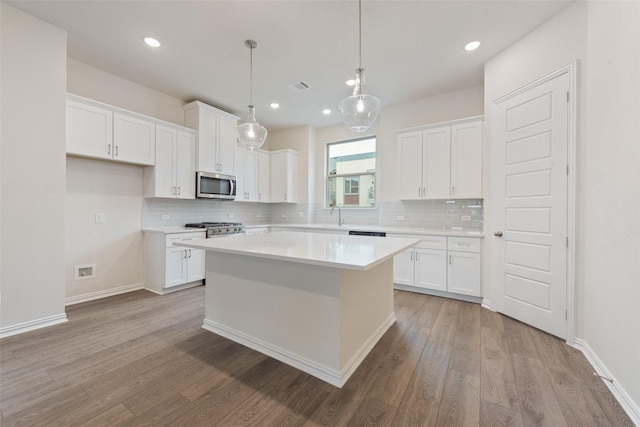 kitchen with light hardwood / wood-style floors, a center island, white cabinets, and appliances with stainless steel finishes