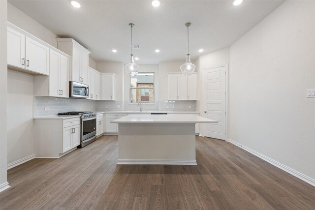 kitchen featuring white cabinetry, appliances with stainless steel finishes, a kitchen island, and pendant lighting