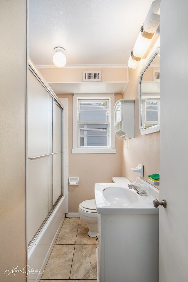 full bathroom with tile patterned flooring, vanity, toilet, and bath / shower combo with glass door