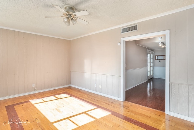 spare room featuring crown molding, ceiling fan, wood-type flooring, and a textured ceiling