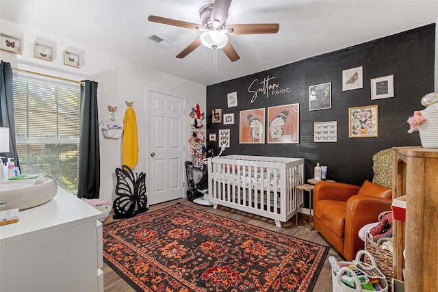 bedroom featuring hardwood / wood-style floors, a crib, sink, and ceiling fan